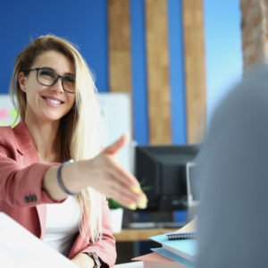 Interview Preparation An image depicting a beautiful woman in a suit happily greeting a man, illustrating the importance of professional demeanor and interpersonal skills in interview preparation.