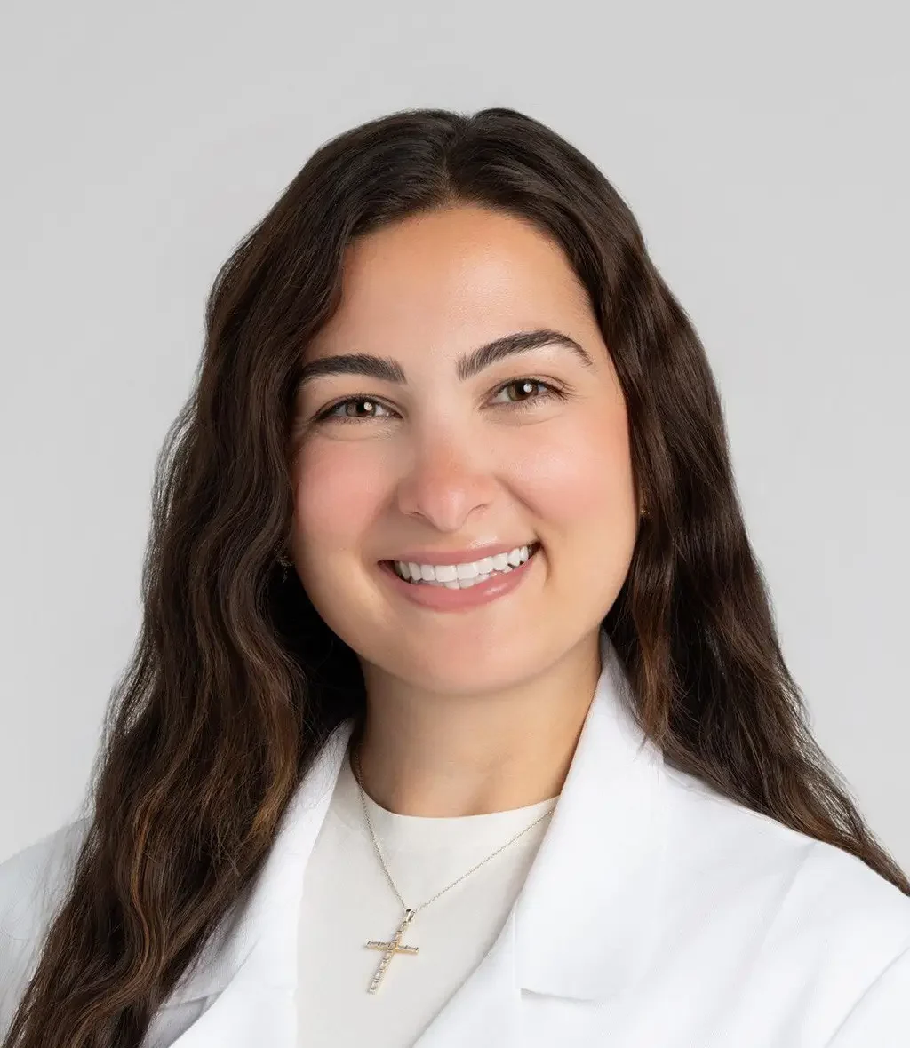 Heya Batah, in a medical coat, smiling confidently. Internal Medicine Resident at The Cleveland Clinic.