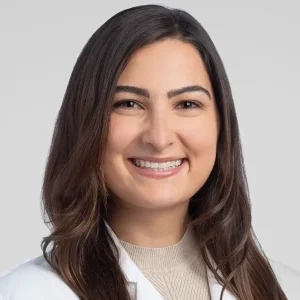 Heya Batah, in a medical coat, smiling confidently. Internal Medicine Resident at The Cleveland Clinic.
